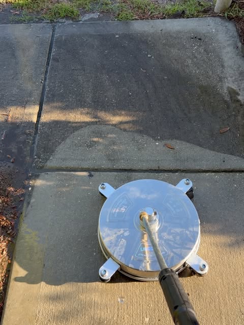 Pressure washer surface cleaner lifting dirt off a concrete sidewalk